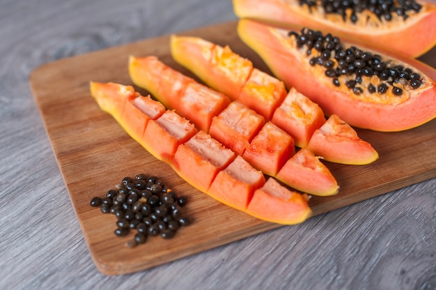 Papaya fruit cut in slices on wooden background