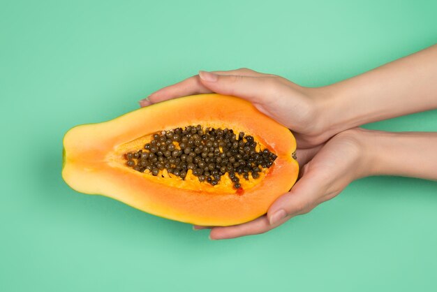 Papaya fruit on a green background in woman hands. Tropical fruit. Half papaya.