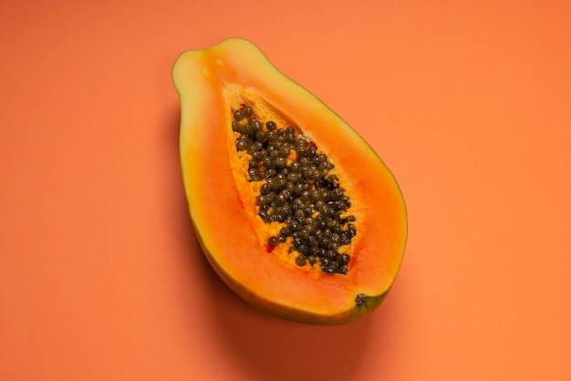 Papaya fruit on a orange background. Tropical fruit. Half papaya.