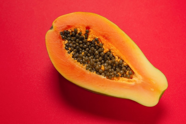 Papaya fruit on a orange background. Tropical fruit. Half papaya.