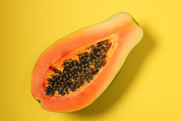 Papaya fruit on a yellow background. Tropical fruit. Half papaya.