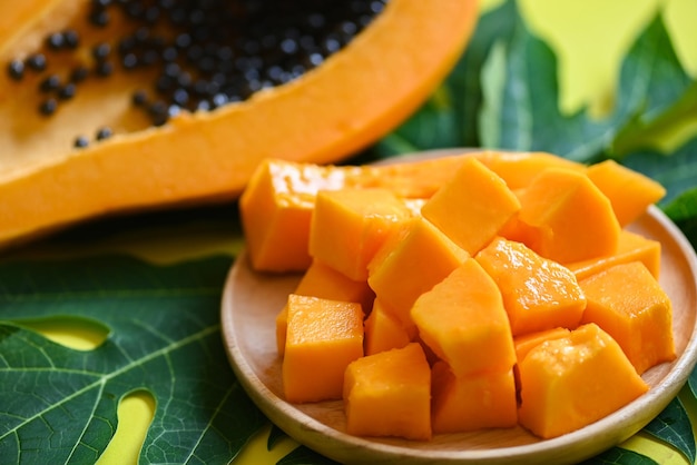 Papaya fruits on wooden backgroud fresh ripe papaya slice on\
plate tropical fruit with papaya seed and leaf leaves from papaya\
tree