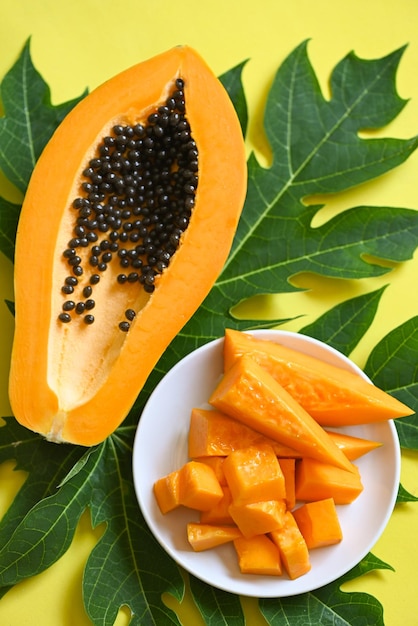 Papaya fruits on yellow backgroud fresh ripe papaya slice\
tropical fruit with papaya seed and leaf leaves from papaya\
tree