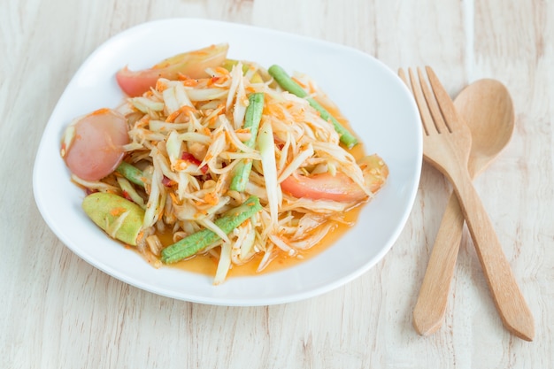 Papaya salad in a white plate on a wooden table,Local thai food