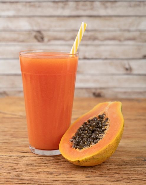 Papaya SAP in een glas met fruit over houten tafel.