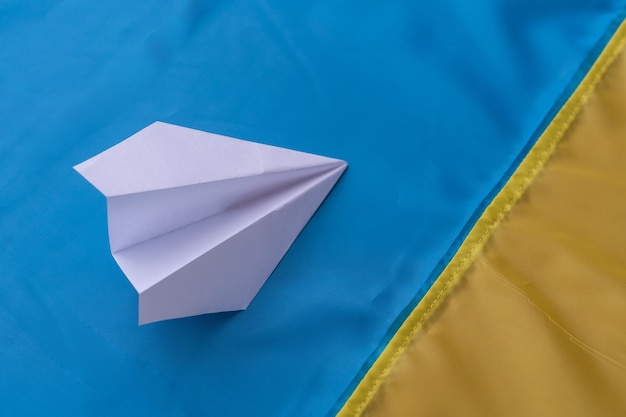 Paper airplane on the background of the flag of Ukraine