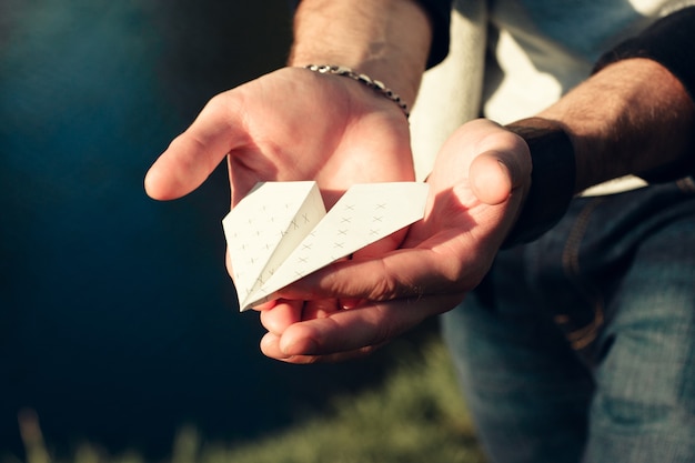 Paper airplane in male hands close-up.