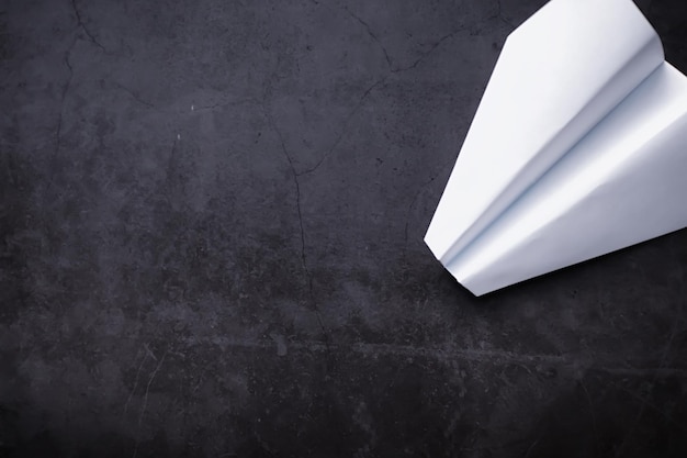 テーブルの上の紙飛行機。暗い背景の折り紙モデル。コンセプト。時間の創造的な無駄。