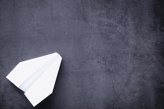 Paper airplane on the table. Origami model on a dark background. Concept. Creative waste of time.