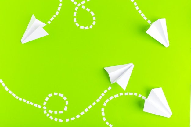 Paper airplanes  connected with dotted lines on green background. Business concept