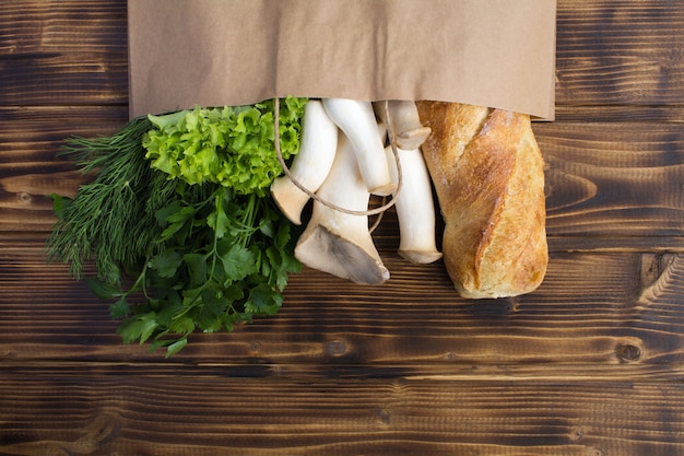 Paper bag of different health food on the brown wooden