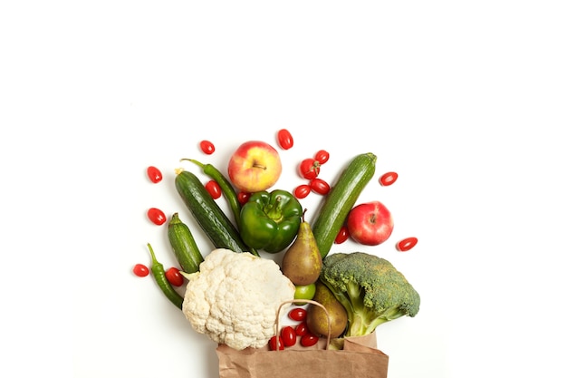 Paper bag of different healthy farm vegetables and fruits isolated on a white background. Top view. Flat lay with copy space.