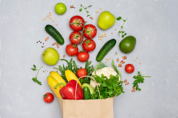 A paper bag full of vegetables and fruits close-up top view. Healthy food, shopping concept, raw food diet.