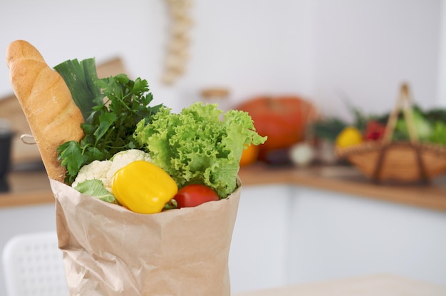 paper bag full of vegetables on the table in kitchen interiors healthy meal and vegetarian concept