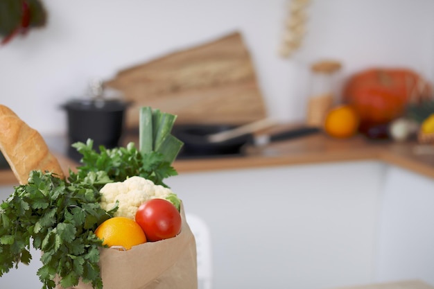 Paper bag full of vegetables on the table in kitchen interiors Healthy meal and vegetarian concept