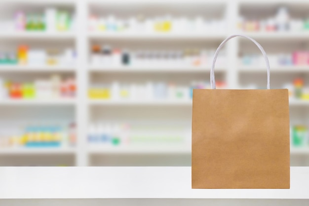 Paper bag on Pharmacy drugstore counter table with medicine on shelves blur background