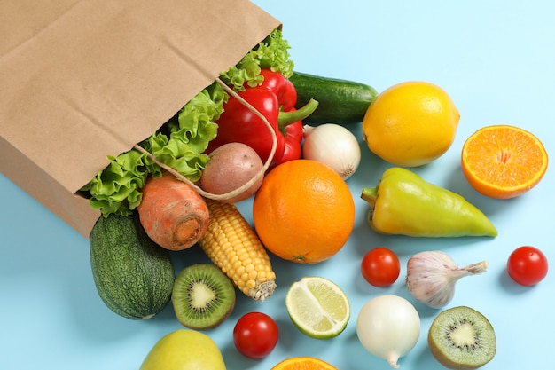 Paper bag, vegetables and fruits on blue space for text