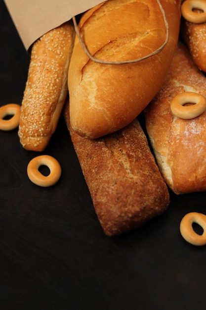 Paper bag with bakery products on a wooden table Baguettes sesame buns long loaf and bagels fresh fragrant crispy pastries Selective focus