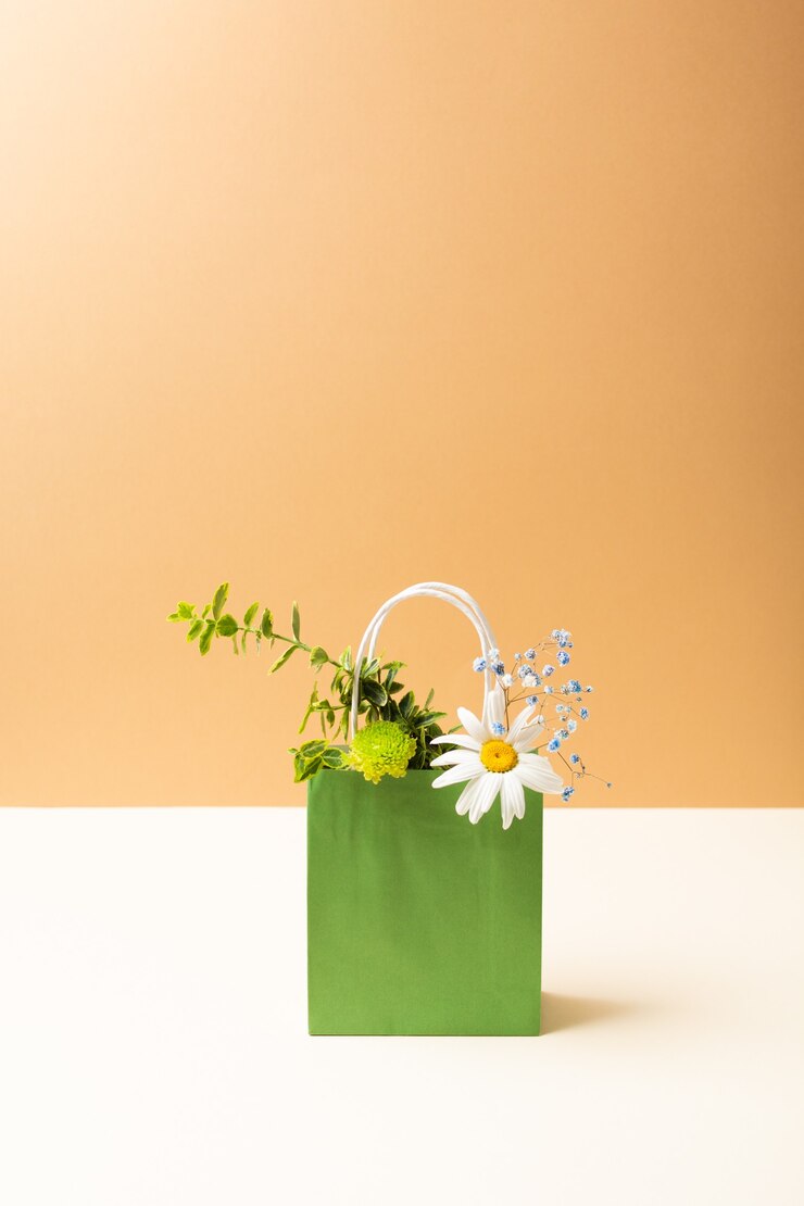 ベージュの背景に美しい夏の庭の花や植物と紙袋