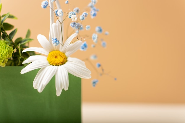 Paper bag with beautiful summer garden flowers and plants on beige background