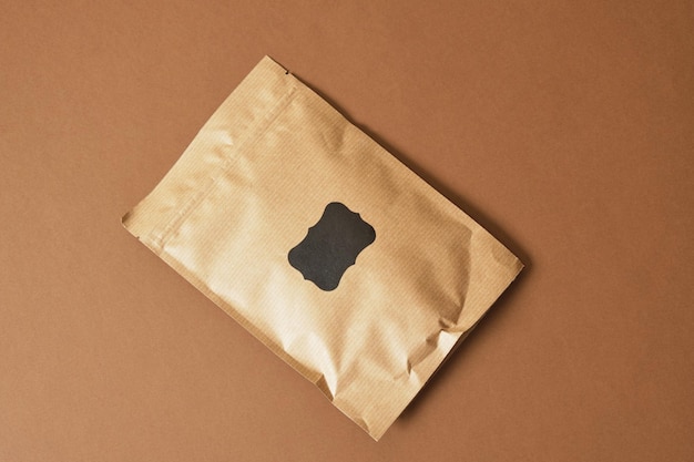 Paper bag with black sticker for inscription on brown\
background eco friendly packaging, paper recycling, zero waste,\
natural products concept. copy space.