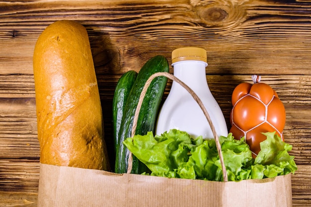 木製のテーブルに食料品とは異なる食品が入った紙袋スーパーマーケットのショッピングコンセプト上面図