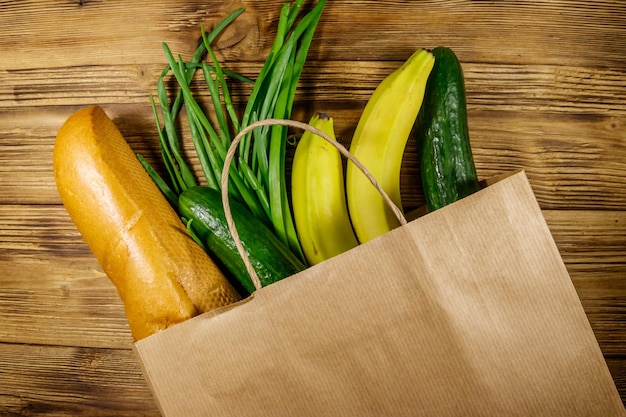 Paper bag with different food on wooden table Top view Grocery shopping concept