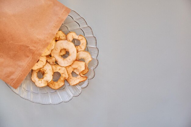 말린 얇게 썬 사과 칩이 있는 종이 가방 접시에 있는 건강한 트렌디한 스낵 Top View 적절한 영양 개념
