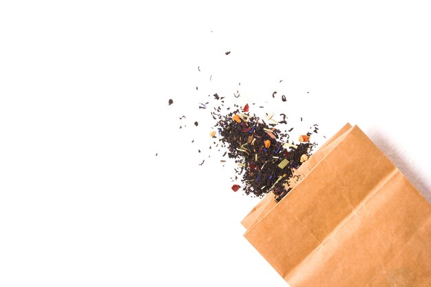 Paper bag with dry loose leaf tea, tea with added fruits, berries and medicinal herbs on a white surface