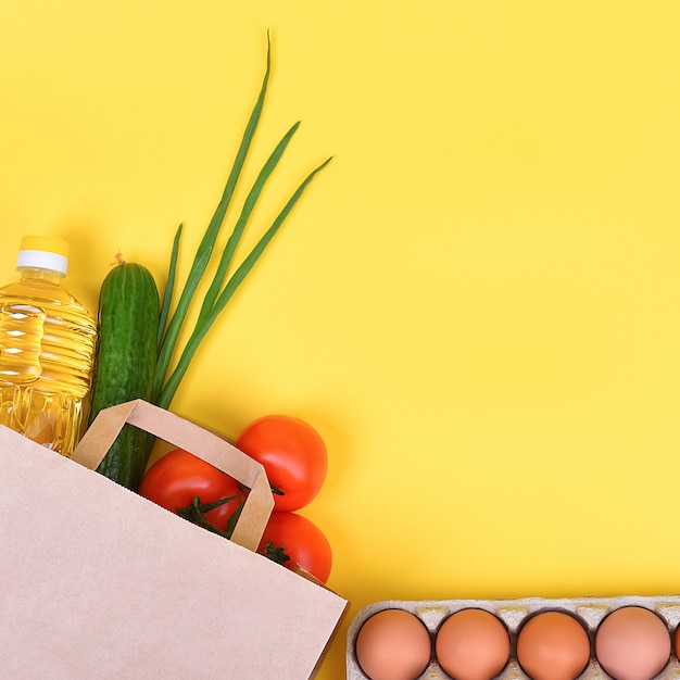 Paper bag with food supplies on yellow background