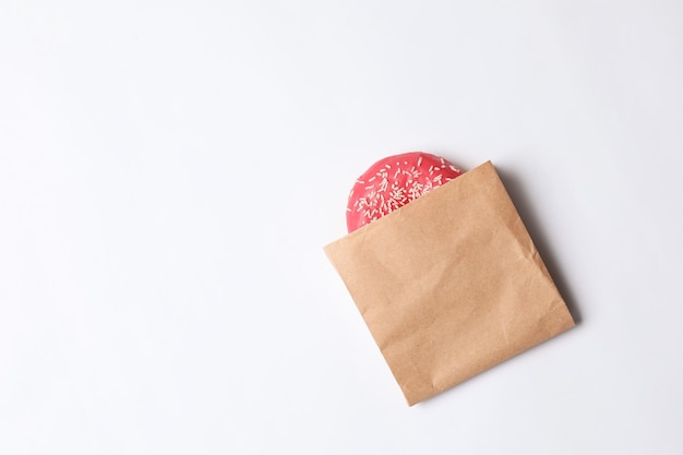Paper bag with glazed doughnut on white background top view Space for text