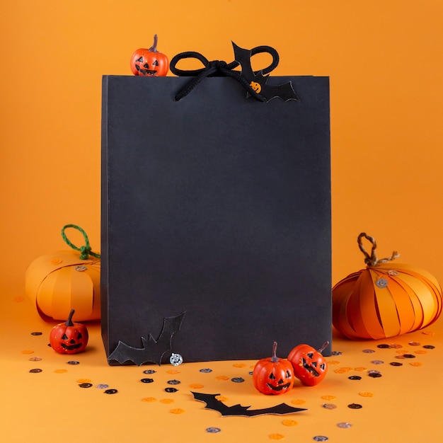 Paper bag with Halloween decorations, pumpkins, bats, confetti. Holiday shopping and sale concept.