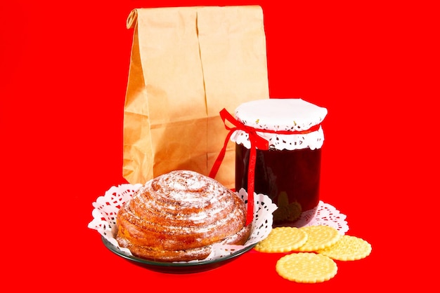 Paper bag with pastry bun and jam on a red background