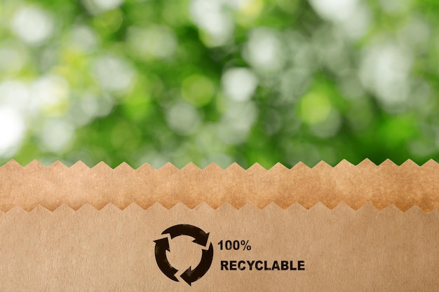 Фото Бумажный пакет с символом переработки на размытом зеленом фоне экологичный пакет