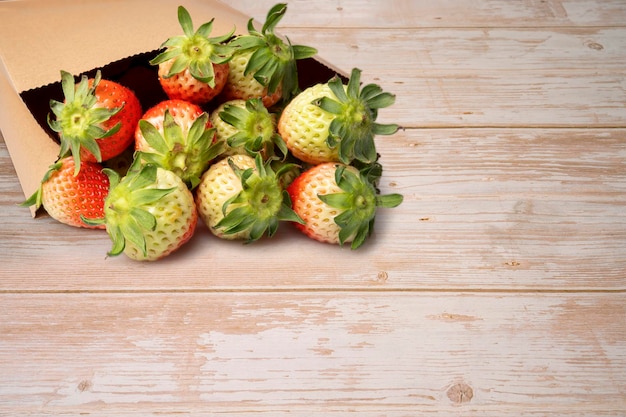 paper bag with strawberries on wooden background