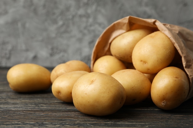 Paper bag with young potatoes on wooden surface