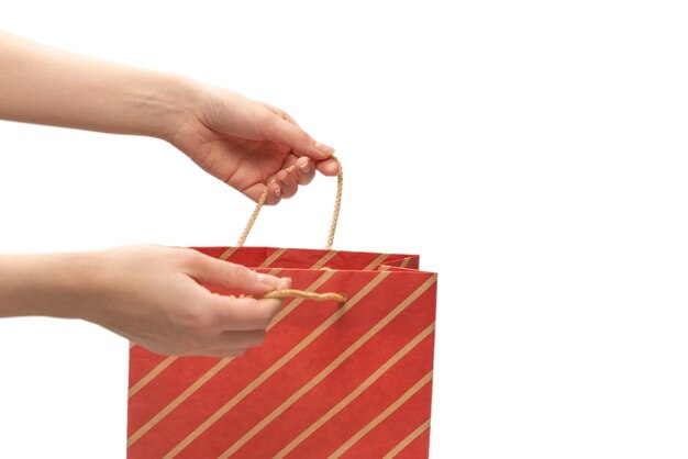 Paper bag in woman hands isolated on white wall.