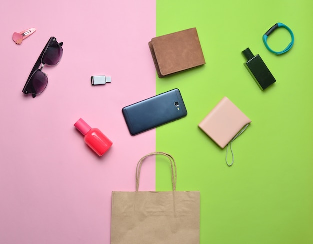 Paper bags and many purchases of gadgets and accessories on a colored background: sunglasses, smartphone, smart bracelet, powel bank, usb flash drive, wallet. Consumer concept. Top view.