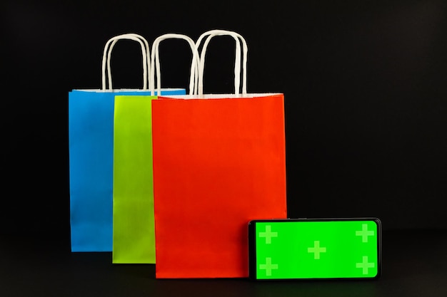 Paper bags red, green, blue phone with a green screen on a black background,ale, promotion, shopping