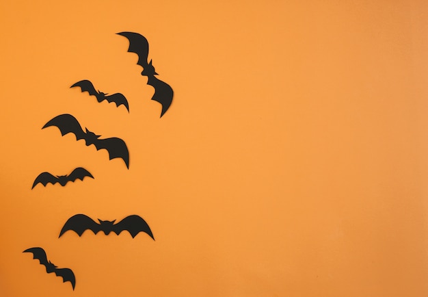 Paper bats flying on orange background. Halloween decoration concept