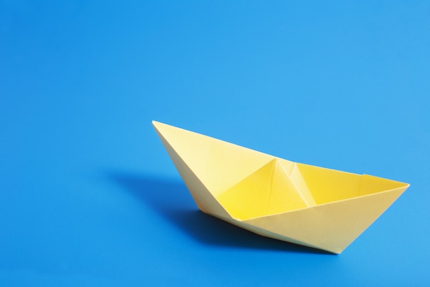 Paper boat on blue paper background