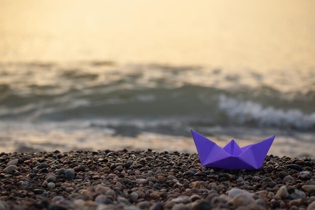 Paper boat by the sea at sunset