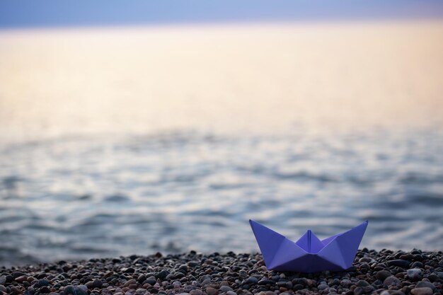 Paper boat by the sea at sunset