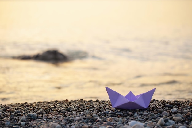 Paper boat by the sea at sunset