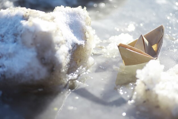 写真 通りの水の中の紙の船。早春のコンセプト。雪解けと水の波で折り紙のボート。