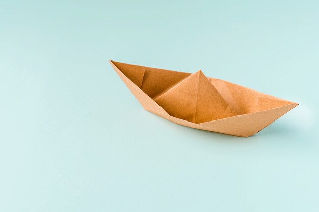 Paper boat on a light blue background, space for text