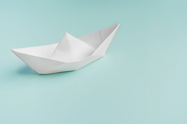 Paper boat on a light blue background, space for text