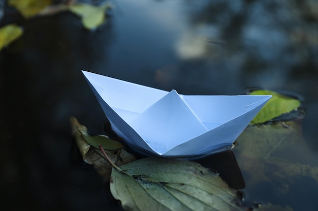 Paper boat in puddle outdoor in rainy weather