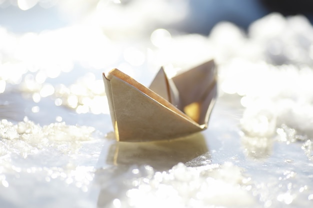 Photo paper boat in the water on the street. the concept of early spring. melting snow and an origami boat on water waves.