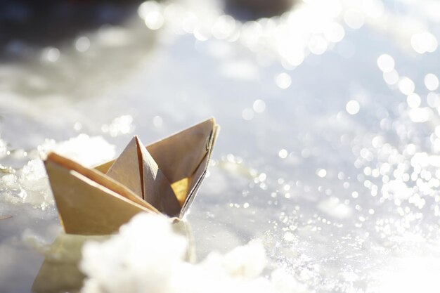 Paper boat in the water on the street. The concept of early spring. Melting snow and an origami boat on water waves.